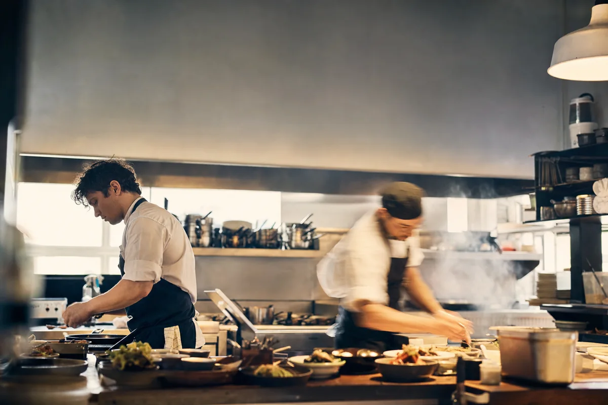 Two chefs working a busy restaurant kitchen line